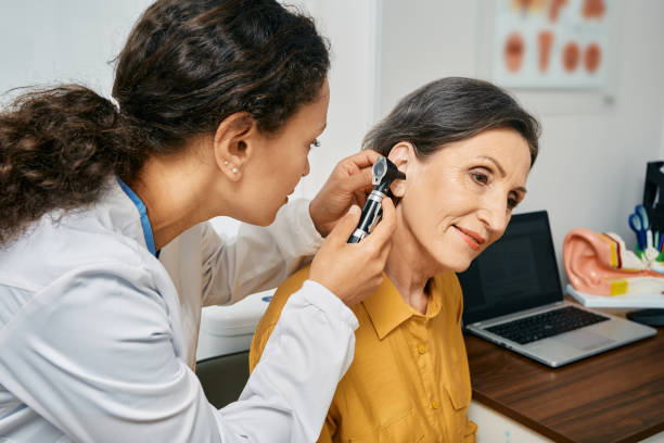 An audiologist checking patients ears